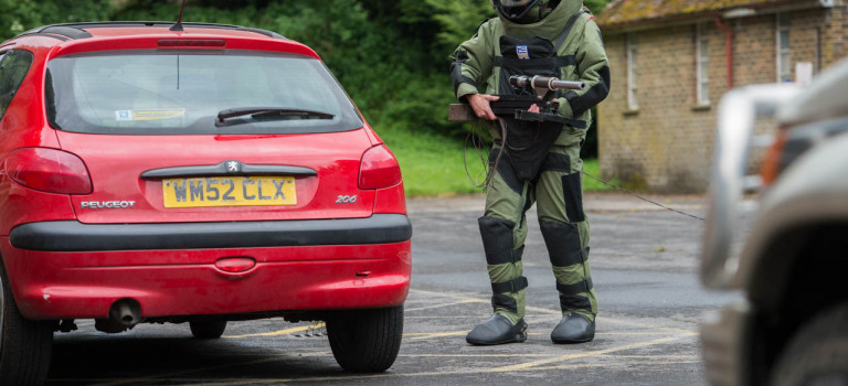 An improvised explosive device disposal specialist searching a car as part of IEDD training